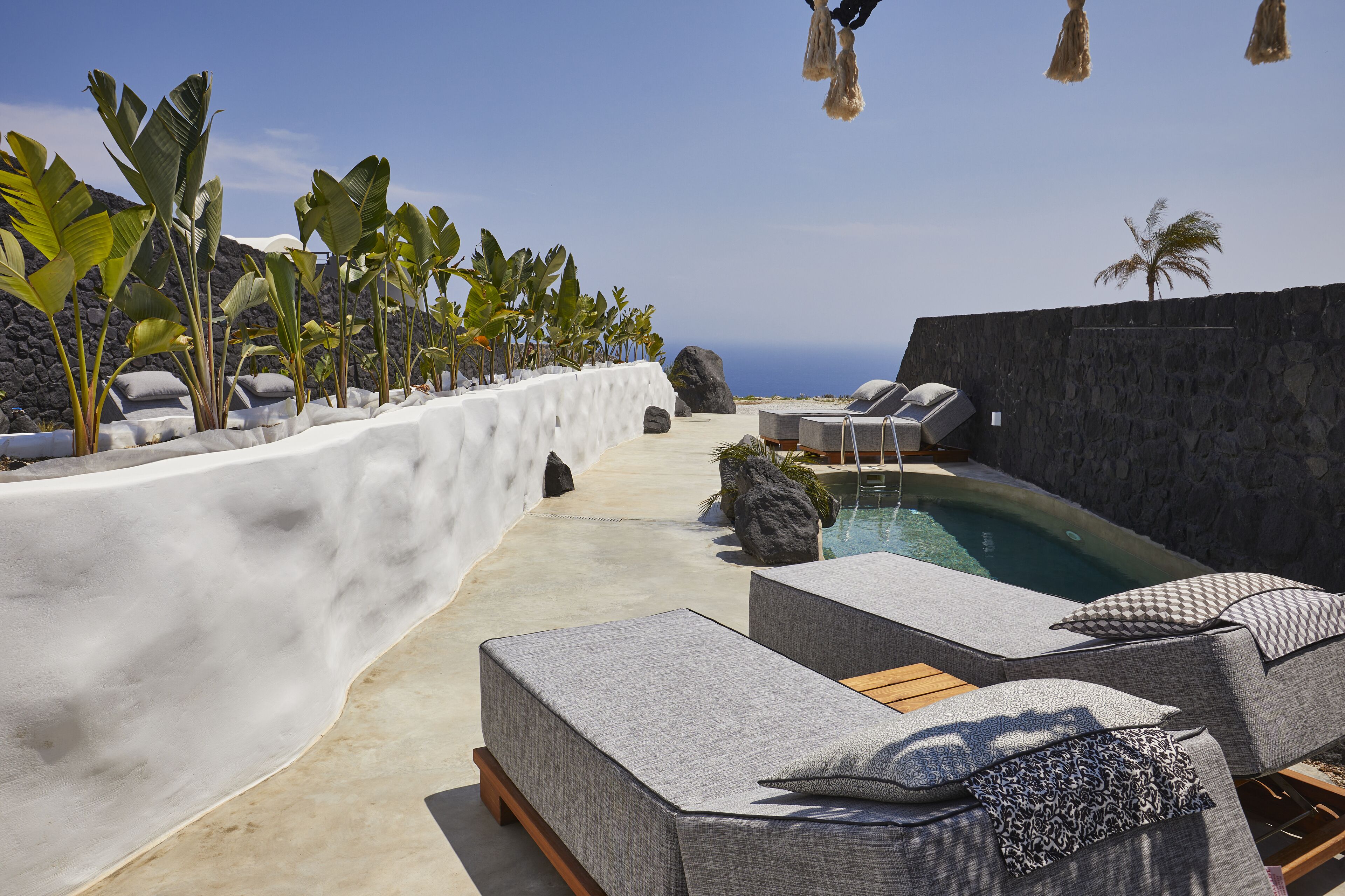 Un espace aménagé au bord de la piscine, avec des chaises longues et une vue sur l’océan.