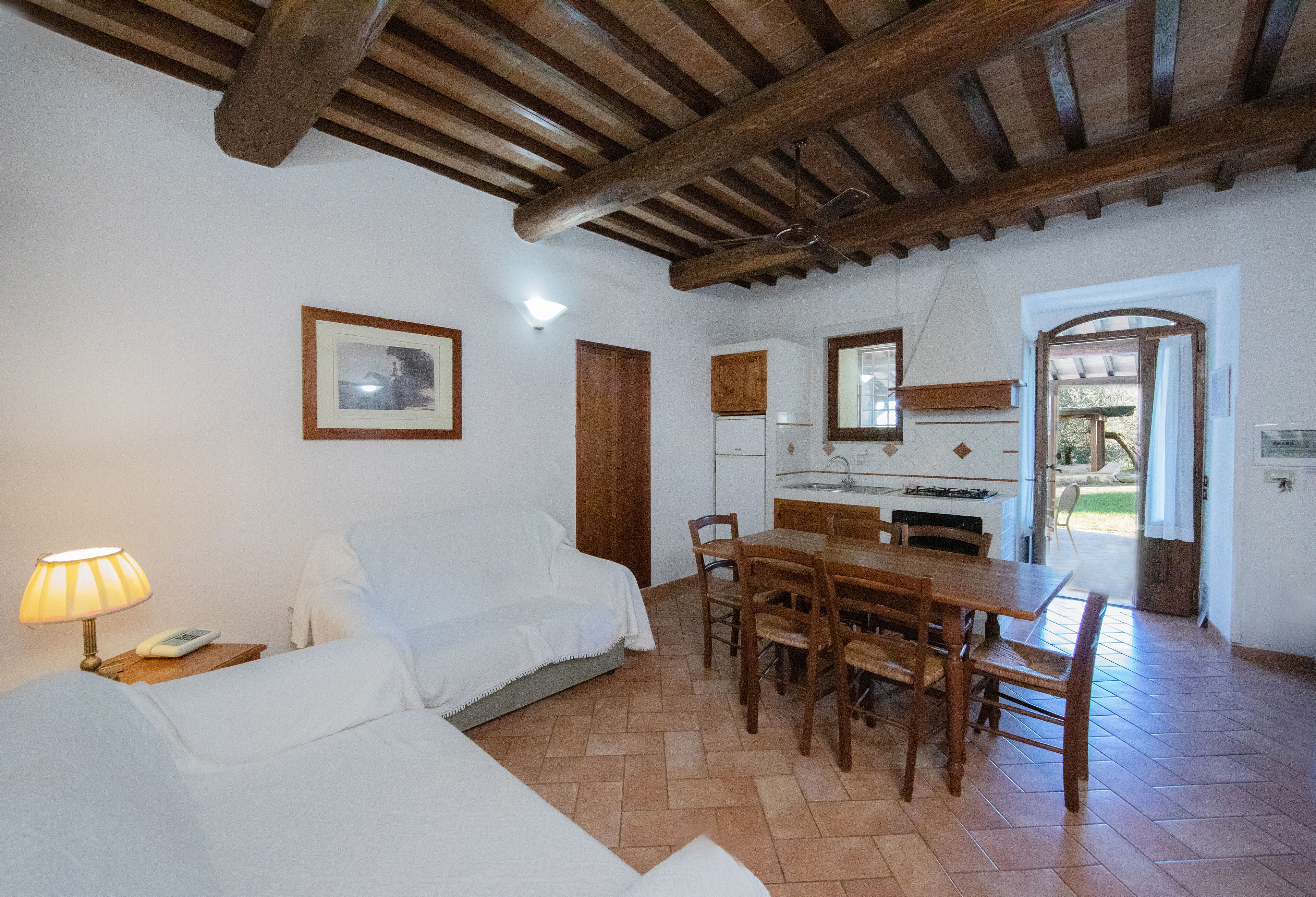 Una habitación acogedora con una cama, una mesa de comedor con sillas, una zona de cocina y techo de madera.