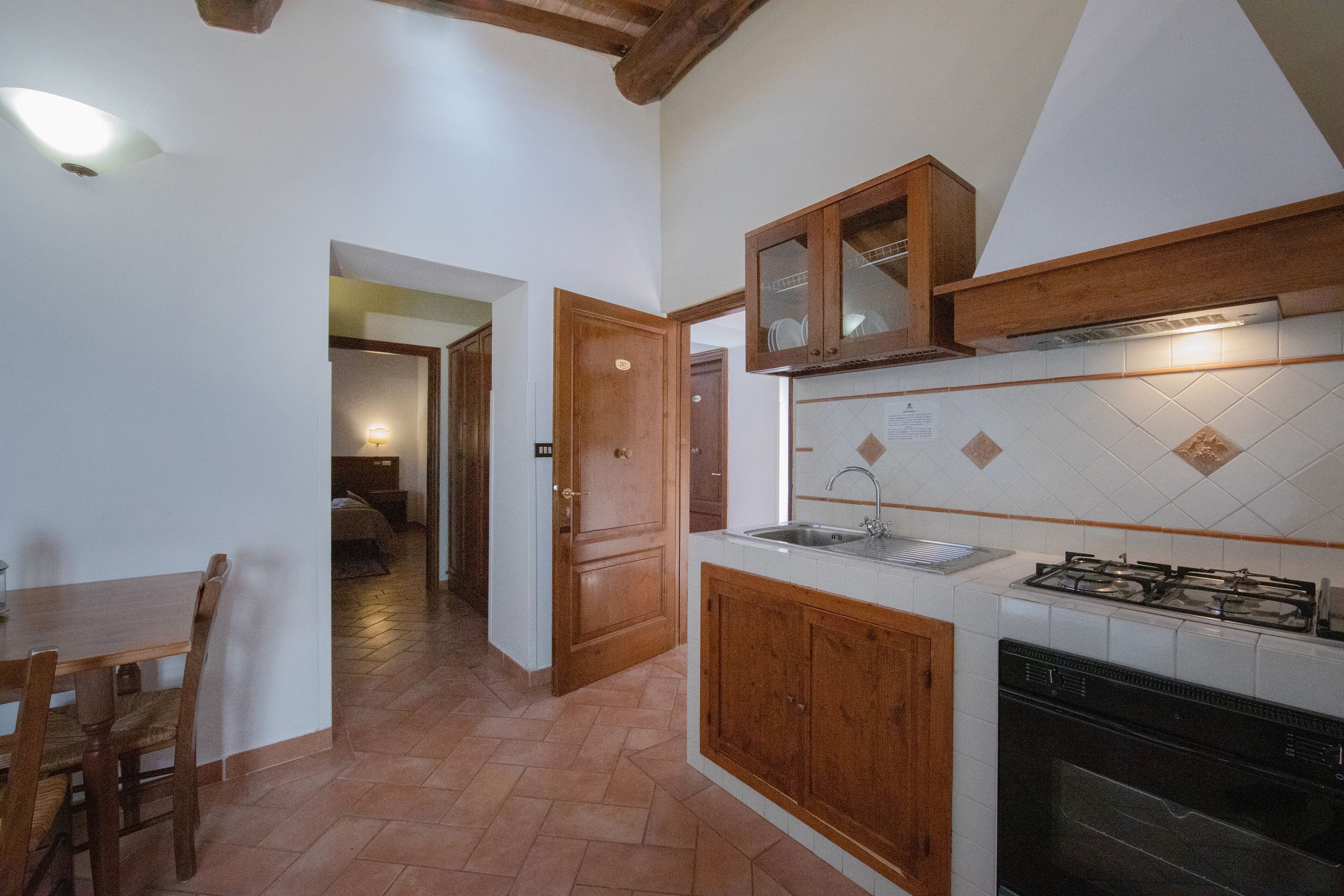 Une cuisine avec des meubles en bois, une cuisinière à gaz et un dosseret carrelé.