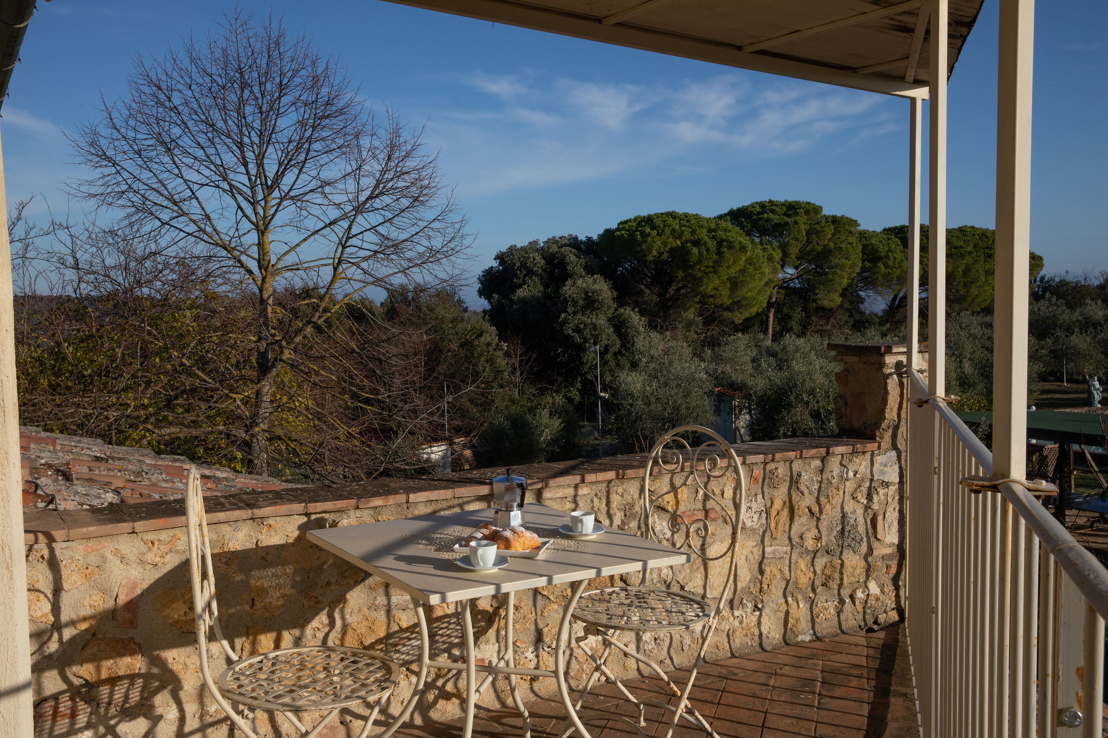 Une terrasse avec une table dressée pour deux personnes, une chaise et un mur de pierres en arrière-plan.