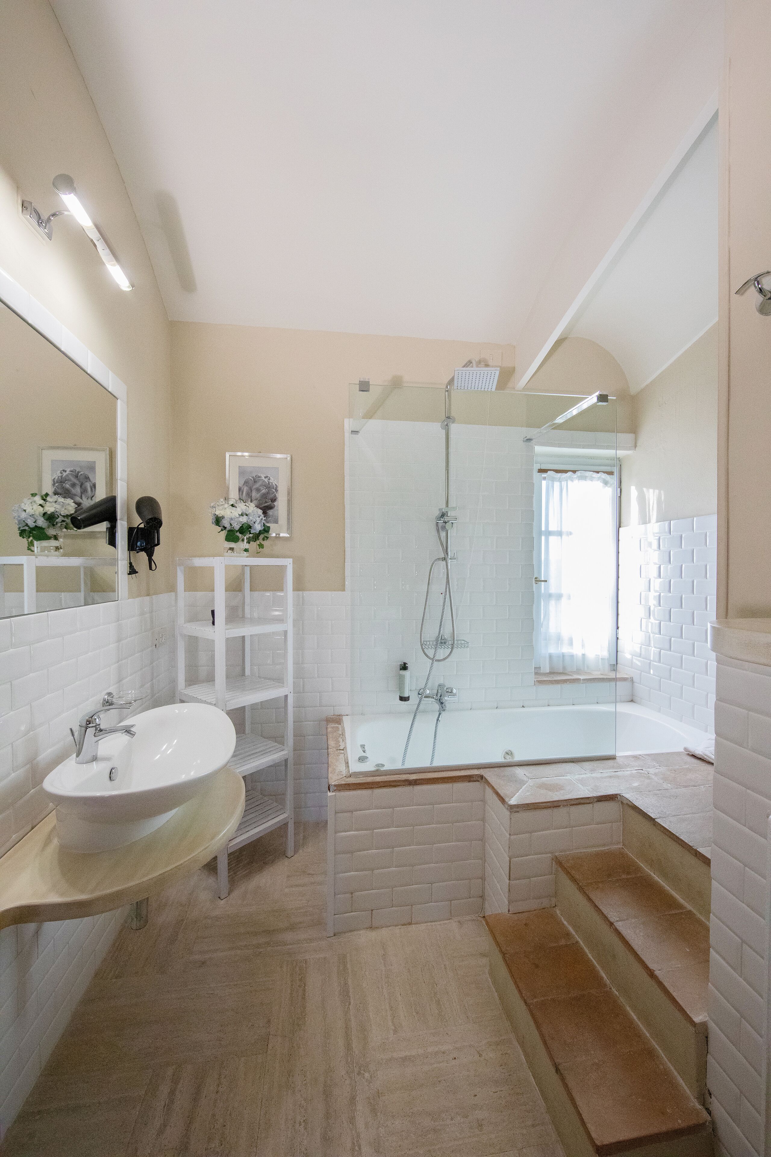 Un bagno con un lavandino bianco, una cabina doccia in vetro e un mobile bagno bianco.