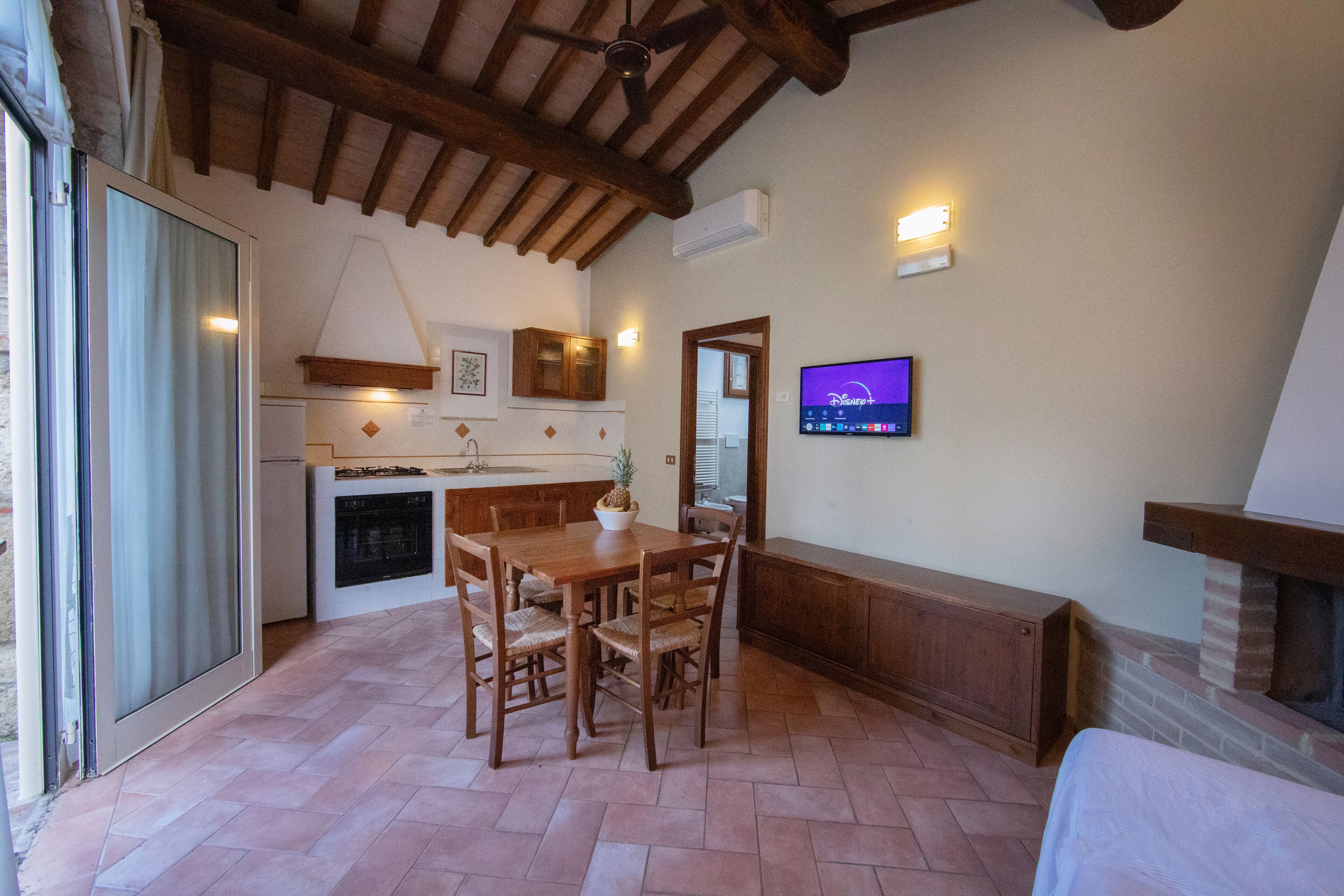 Un rincón comedor acogedor con una mesa y sillas de madera, chimenea y televisor fijado en la pared.