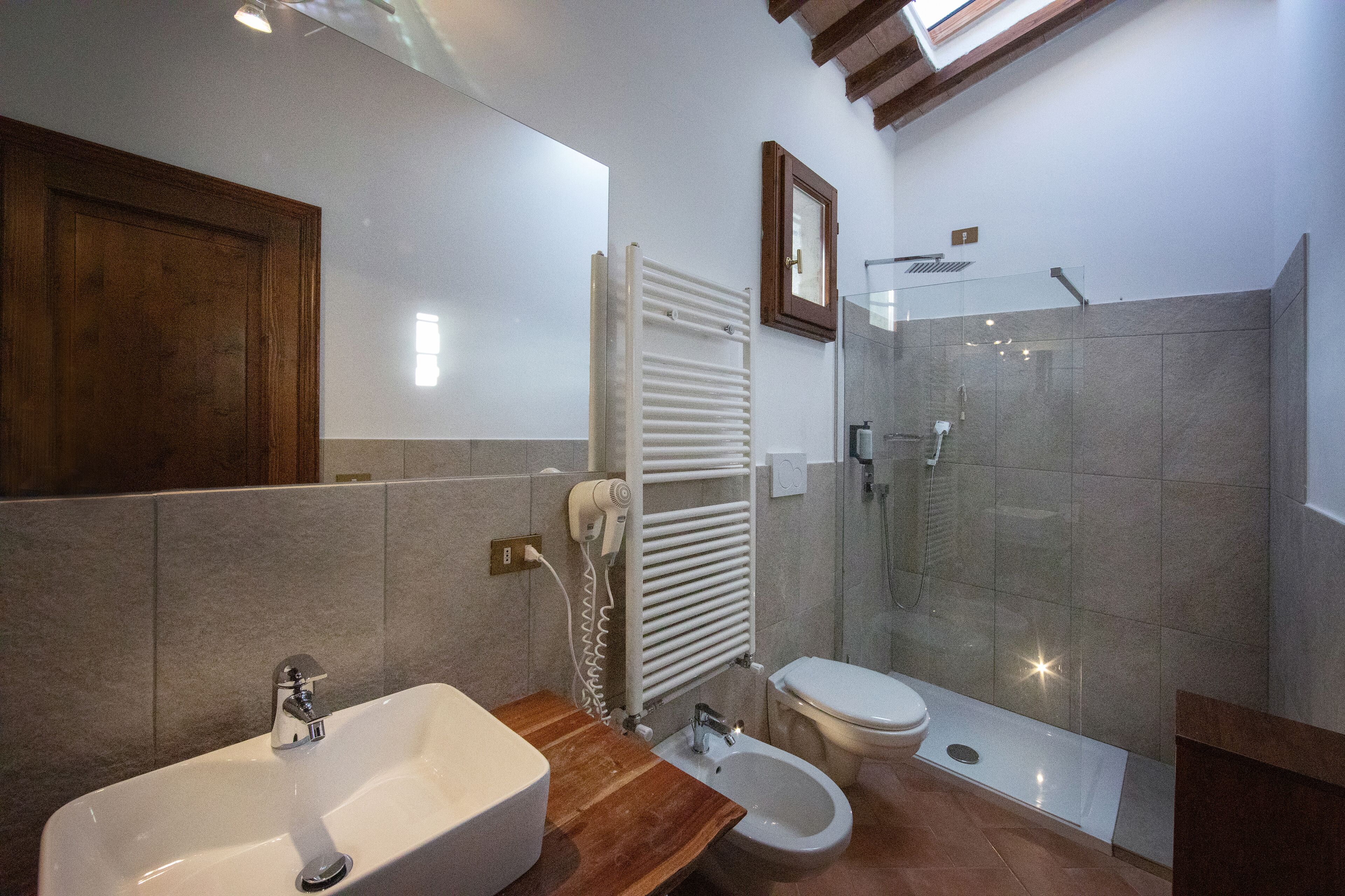 Uma casa de banho moderna com lavatório, bidé, sanita e cabine de duche com parede de vidro.