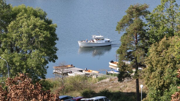 A boat on calm water surrounded by trees. - Blankaholms Bad och Naturcamping (Hjorted)