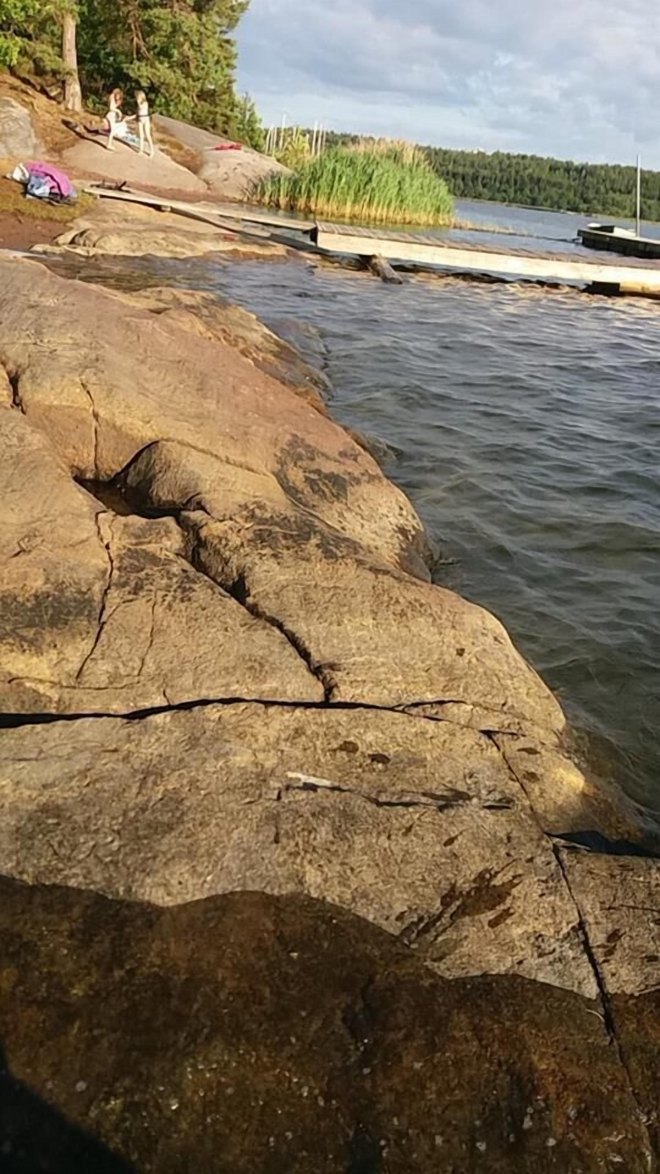 Une côte rocheuse avec une jetée qui s’avance dans une eau calme.