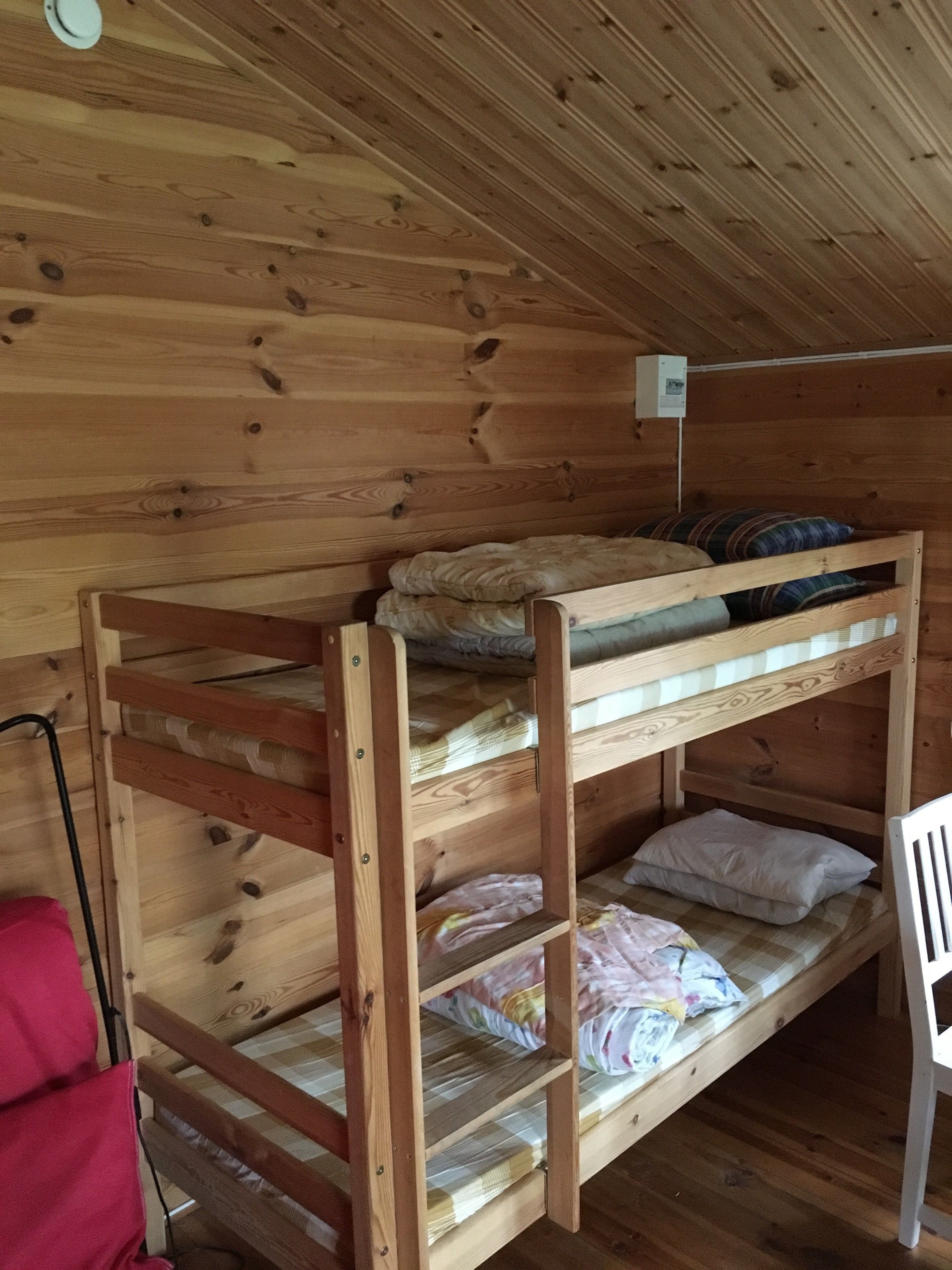 A bunk bed with wooden walls and a ceiling light.