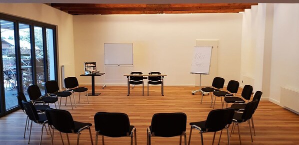 Un salón de conferencias con sillas dispuestas en círculo, una pizarra y una mesa con una computadora portátil.
