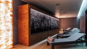 A spa area with wooden walls, a large textured wall art, and several lounge chairs with towels. - Primavera Jastrzębia Góra (Wladyslawowo)