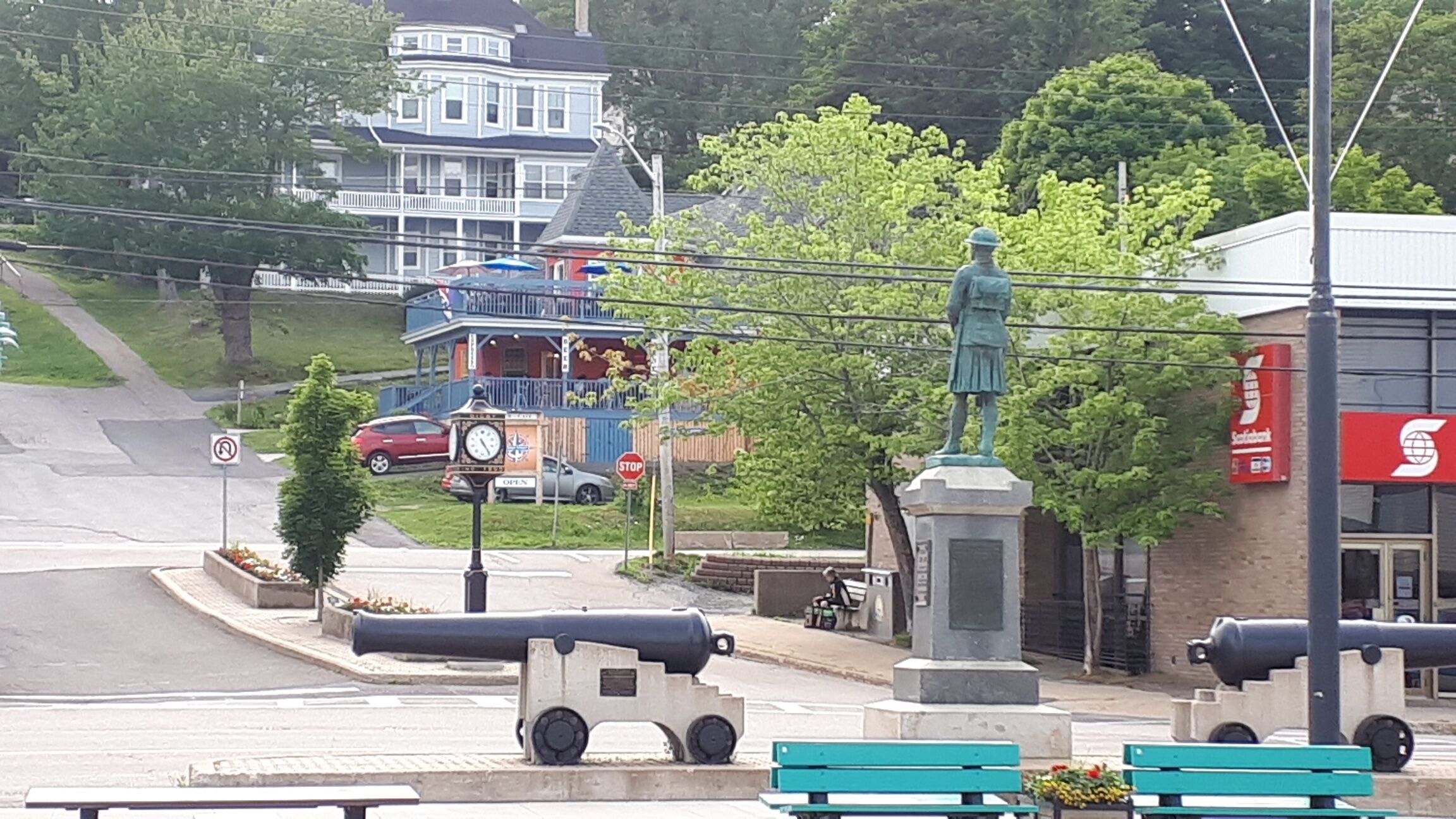Une place publique ornée d’une statue, d’une horloge et de canons.