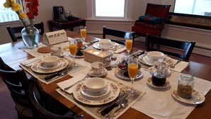 A breakfast setup with floral tableware, a coffee maker, and a vase with flowers. - Hillside Landing B&B (Digby)