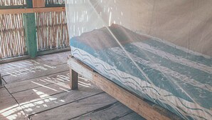 Ein Zimmer mit Holzboden, einem Bett mit gemustertem Matratze und einem kleinen Teppich.