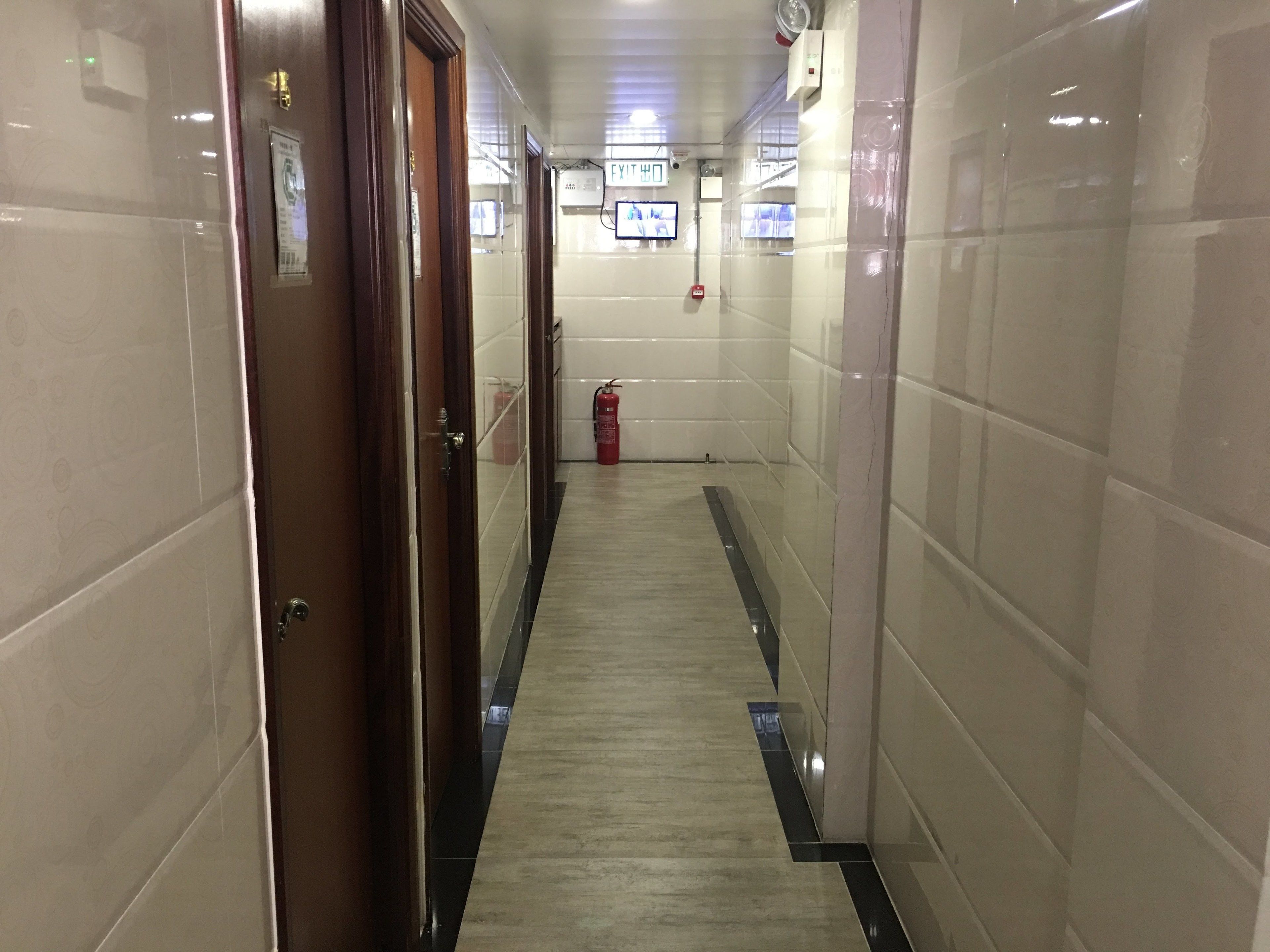A corridor with tiled walls, a fire extinguisher, and a door.