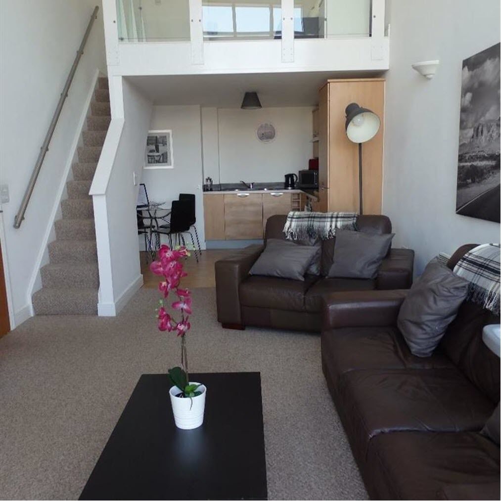 Un apartamento moderno con sala de estar, cocina y escalera.