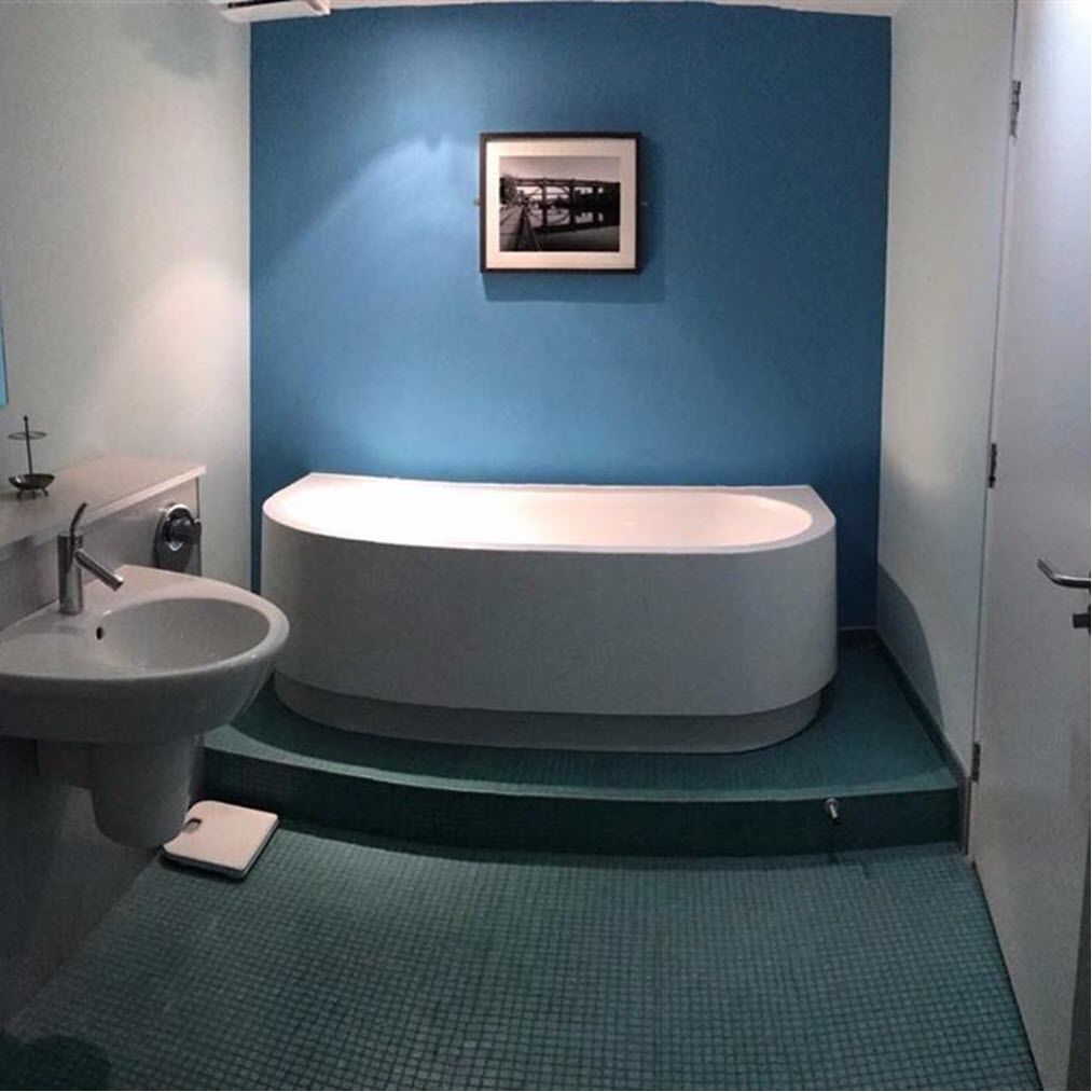 A bathroom with a large bathtub, a sink, and a framed picture on the wall.