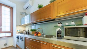 Una cocina moderna con armarios de madera, un lavamanos de acero inoxidable, un microondas y una cafetera.