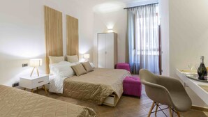 Una habitación de hotel con cama, armario, escritorio con silla y ventana con cortinas.