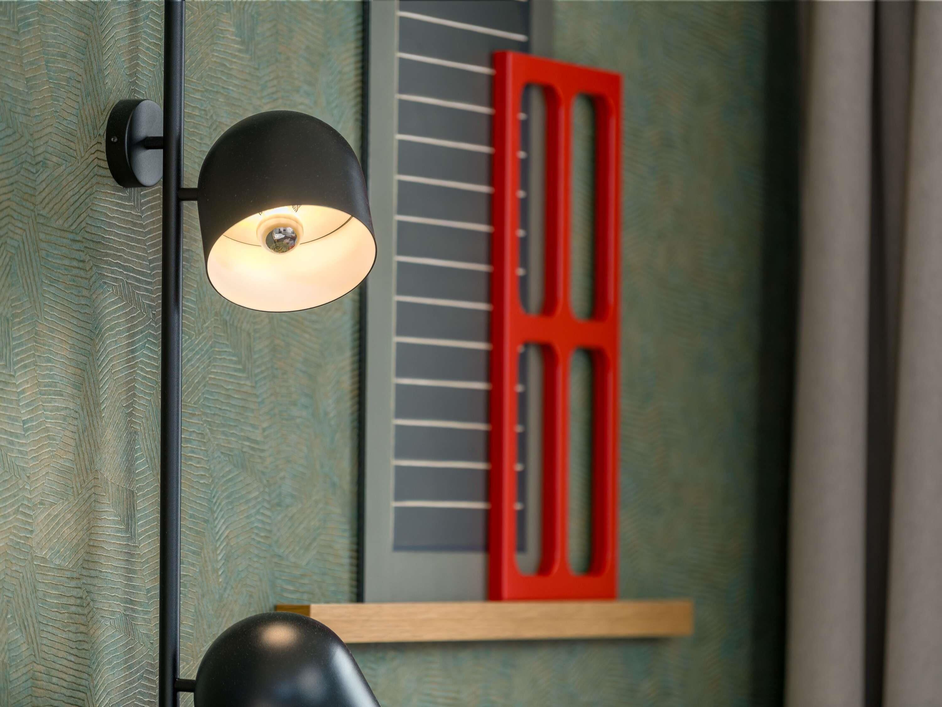 A wall-mounted light fixture with a black shade and a red door frame.
