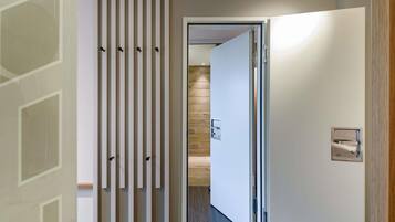 Um corredor com design moderno, apresentando um painel vertical com ganchos, uma porta com puxador e um interruptor de luz na parede.