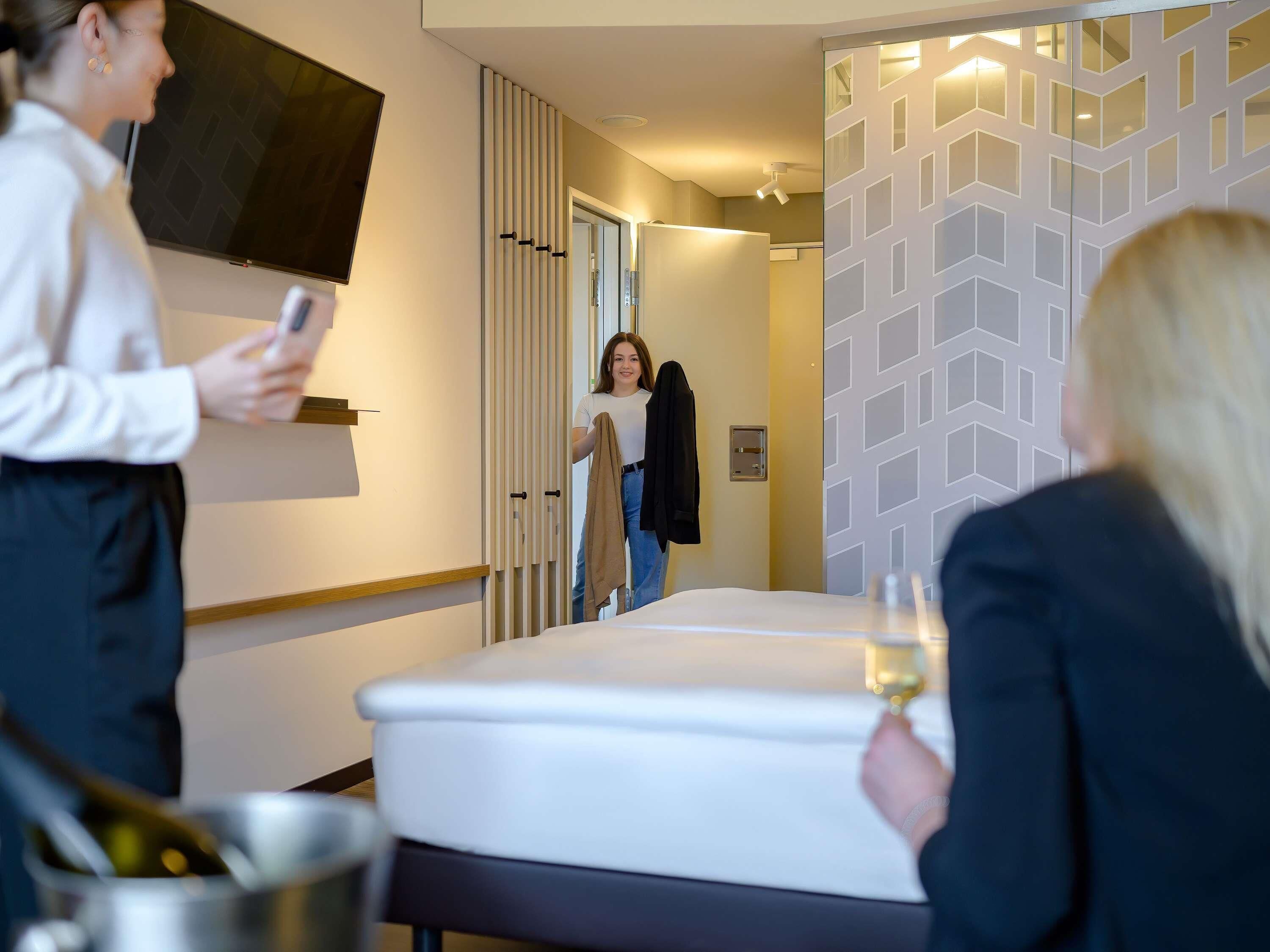 Una habitación de hotel con cama, televisión, minibar y pared con diseño.