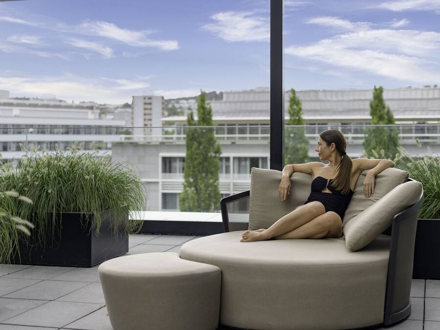 Una mujer sentada en un sofá curvo con vistas a la ciudad.