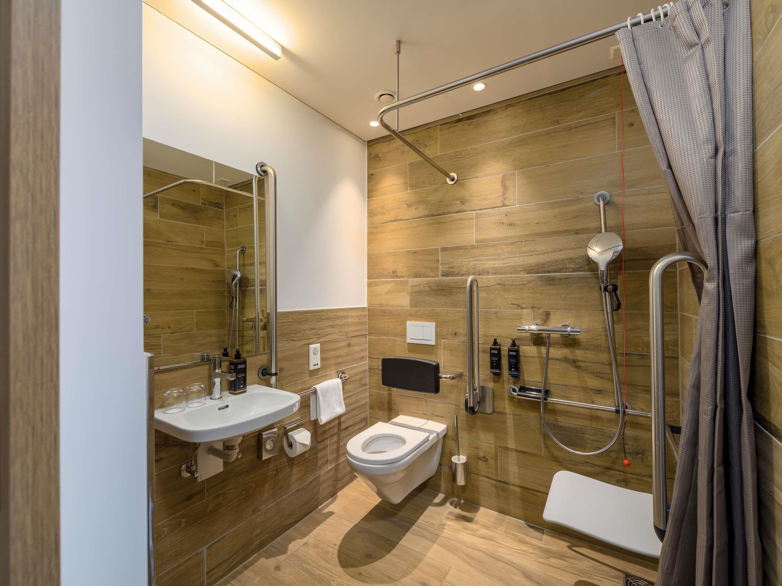 A modern bathroom with a shower, toilet, sink, and a mirror.