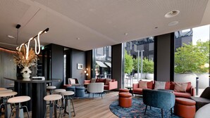 A modern lounge area with a mix of seating options, a bar, and large windows offering views of the outdoors.