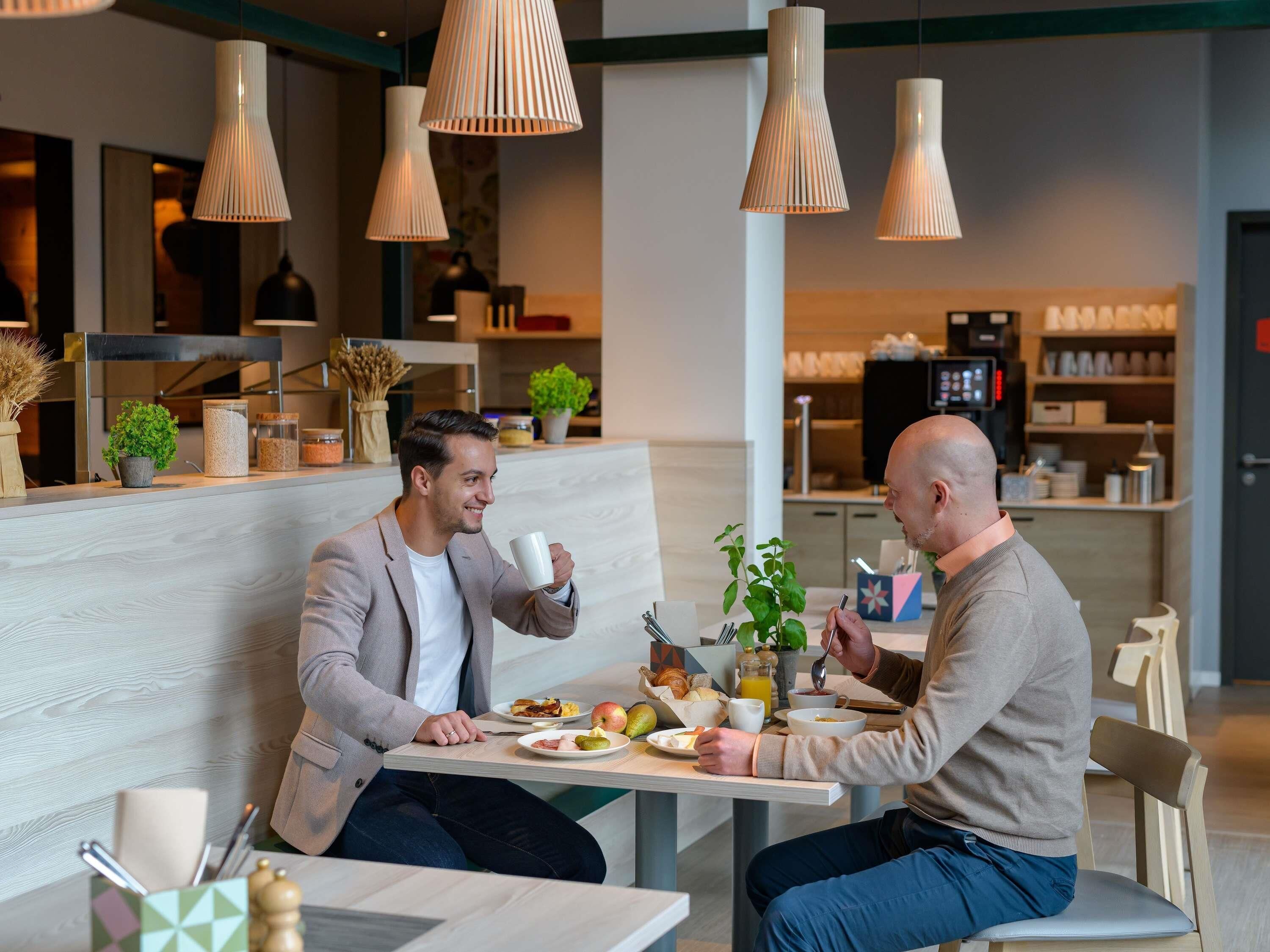Una cafetería moderna con mesas de madera y lámparas colgantes.