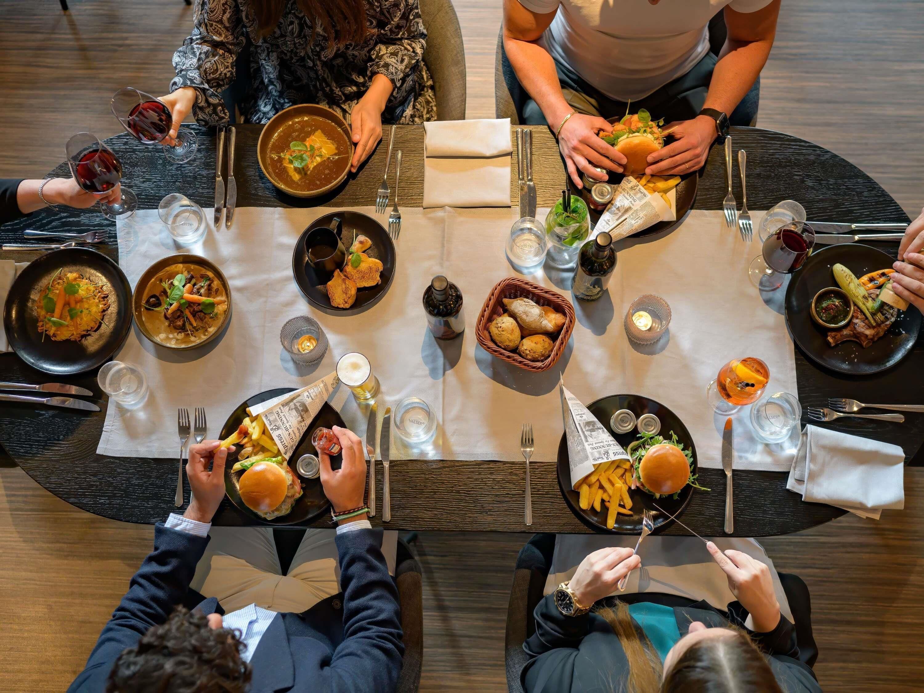 A dining table with multiple plates of food, glasses, and cutlery.