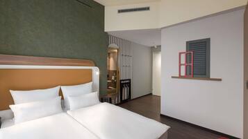 Una habitación de hotel con una cama, un espejo, una silla roja y una obra de arte colgada en la pared.