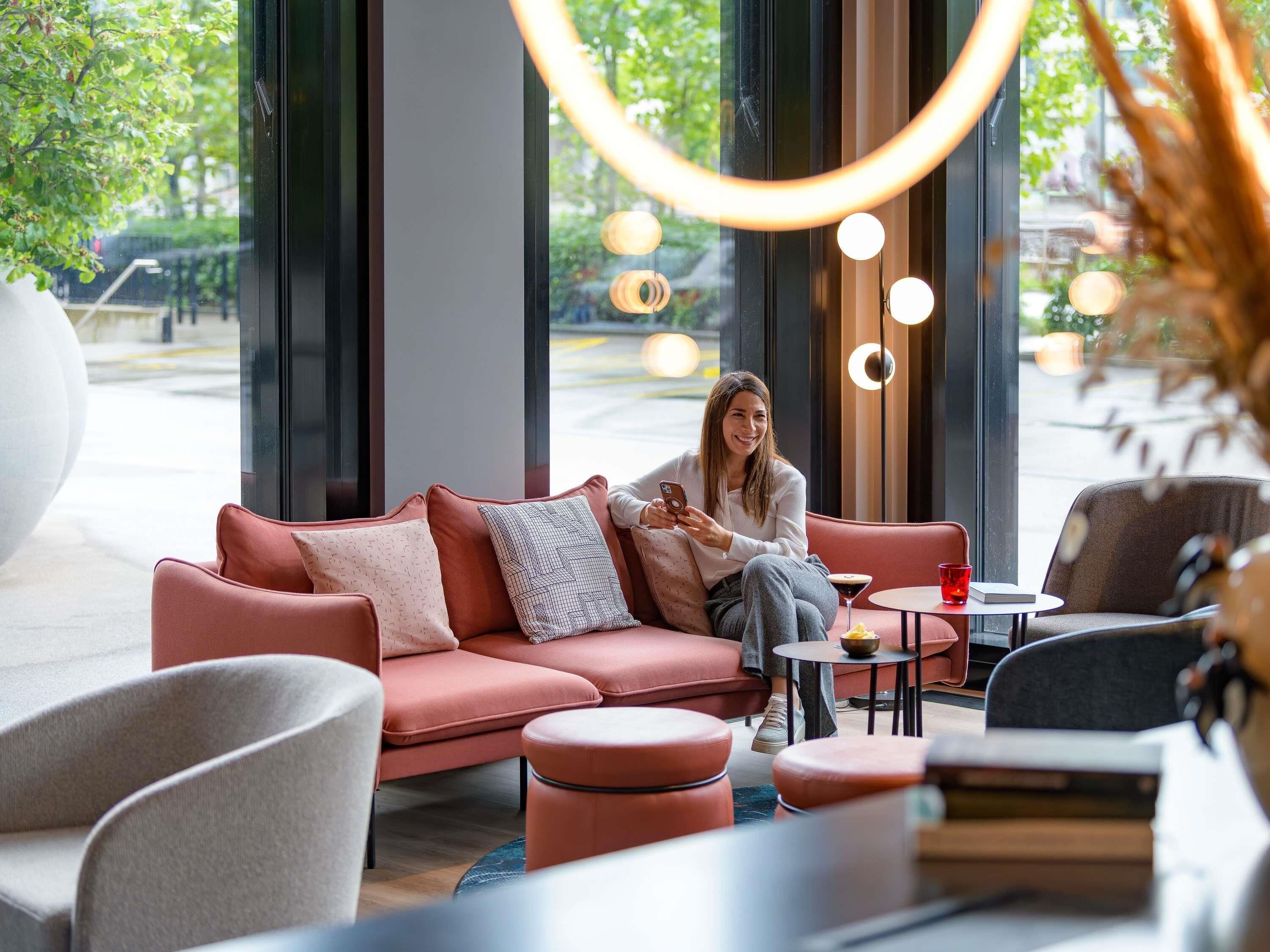 Un intérieur moderne avec un canapé rouge, une petite table ronde et une grande fenêtre laissant entrer la lumière naturelle.