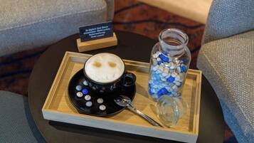 En bakke med en kop kaffe, en ske og et glas perler på et bord.