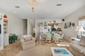 A spacious living room with a sofa, a coffee table, and a dining area with chairs. - Jen's Creole 4 Bedroom Townhouse by RedAwning (Navarre)