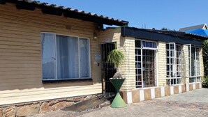 A building with a tiled roof, a large window, and a potted plant. - Johannesburg Youth Hostel (Randburg)