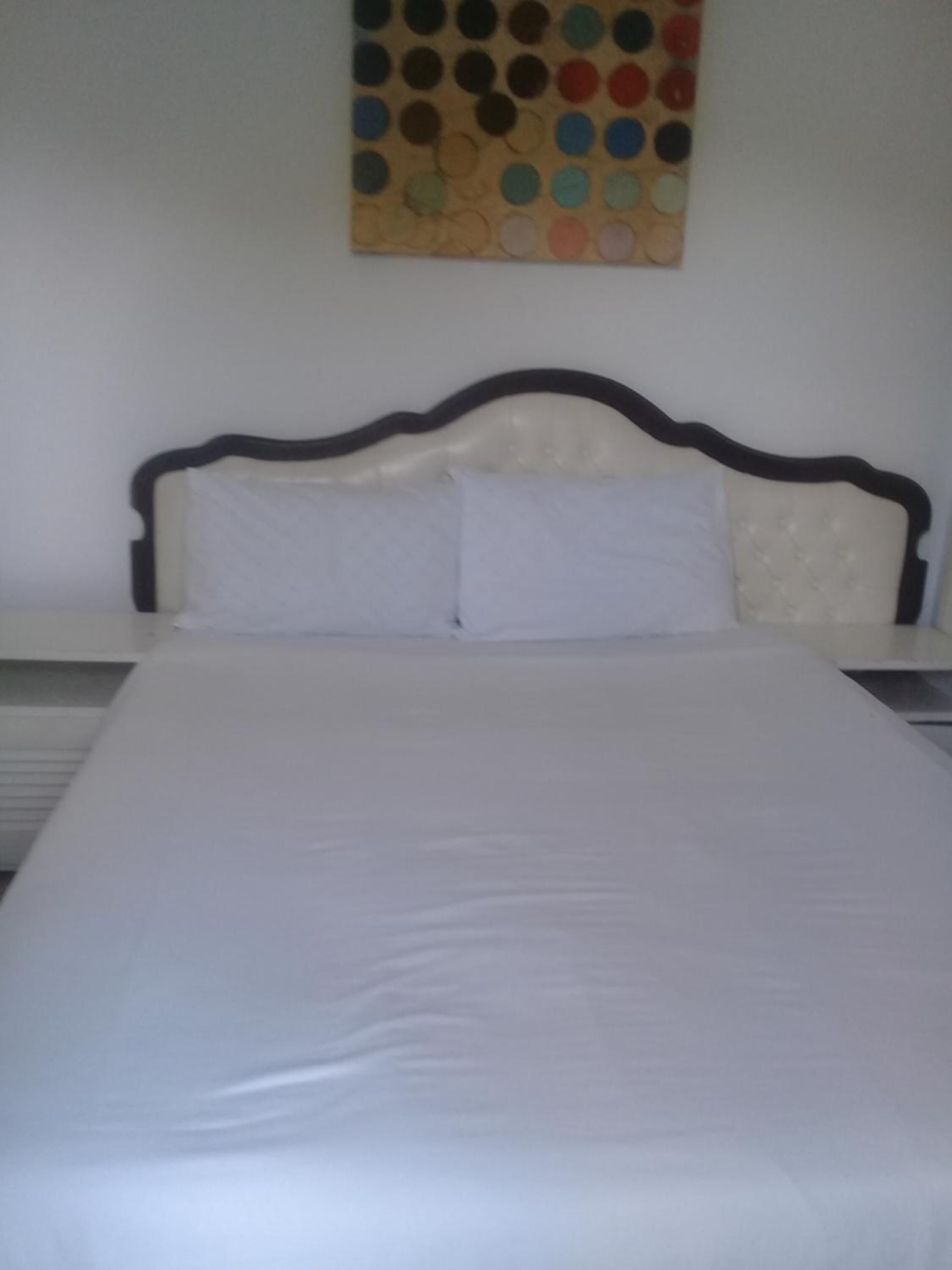 Una cama con colchón blanco y cabecera de madera oscura.