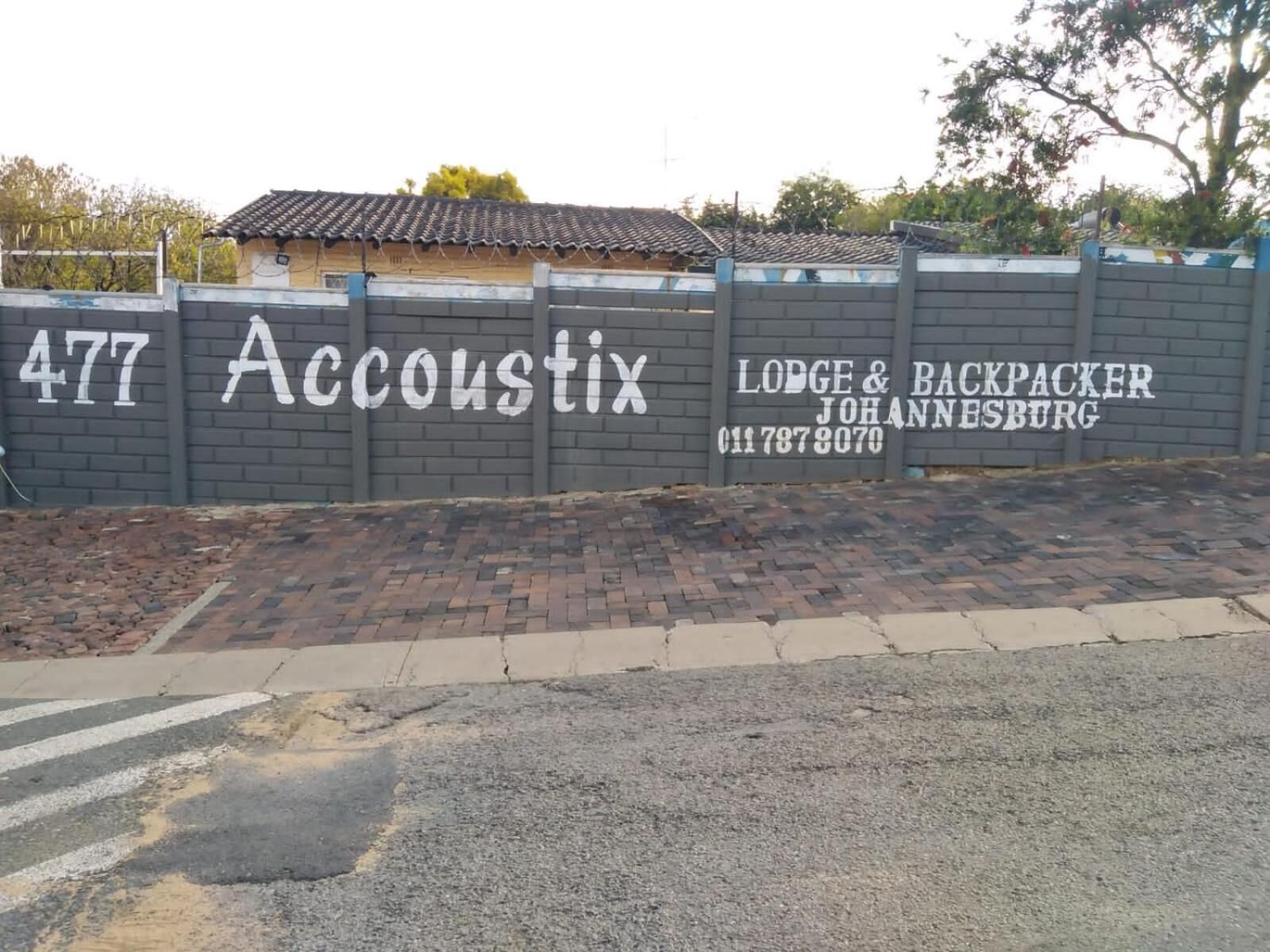 A wall with the number 477 and the name 'Accoustix' along with 'Lodge & Backpacker Johannesburg' and a contact number.