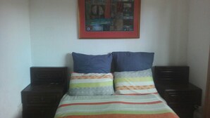 A bedroom with a bed, two nightstands, and a framed picture on the wall. - Fourways Youth Hostel (Sandton)