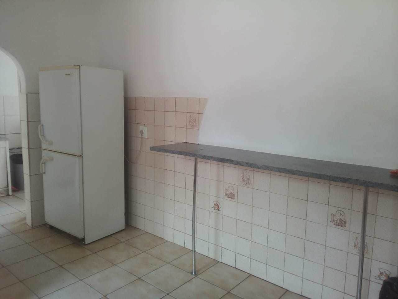 A kitchen with a white refrigerator, tiled backsplash, and a countertop.