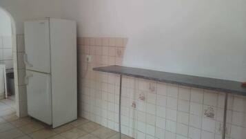A kitchen with a white refrigerator, tiled backsplash, and a countertop.