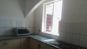 A small kitchen with a microwave, a gas stove, and a window providing natural light. - Fourways Youth Hostel (Sandton)