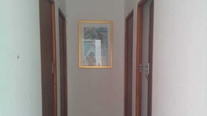 A narrow hallway with tiled flooring and wooden doors on both sides. - Fourways Youth Hostel (Sandton)