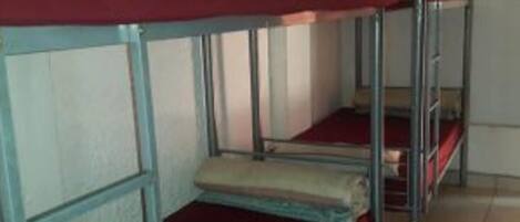 Dormitorio con literas, barandillas de metal y ropa de cama roja.