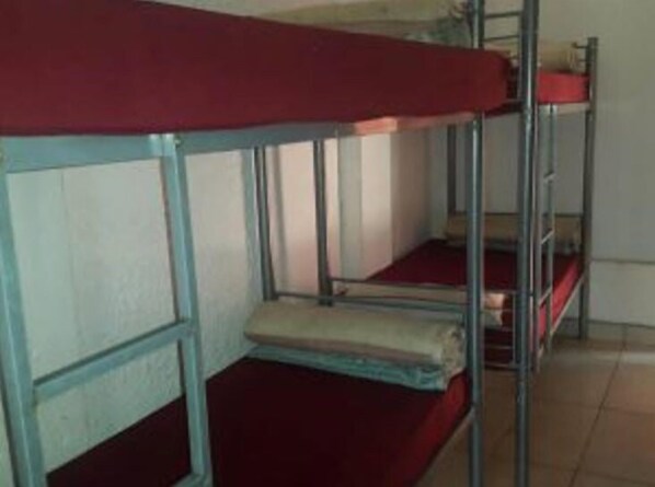 Dormitorio con literas, barandillas de metal y ropa de cama roja.