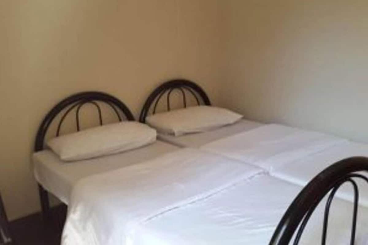 Een eenpersoonsbed met houten frame en wit beddengoed in een kamer met effen muren.
