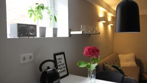 Una cucina moderna con un bollitore, una citazione motivazionale incorniciata, un vaso con un fiore e una finestra con piante.