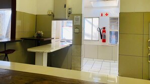 Una habitación pequeña y limpia con kitchenette, extintor y ventana.