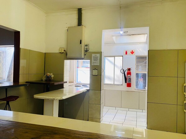 Una habitación pequeña y limpia con kitchenette, extintor y ventana.