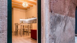 A modern kitchen with wooden cabinets, a dining area with chairs, and a red bench. - Bragora 3524 Between S. Marco & Biennale (Venice)