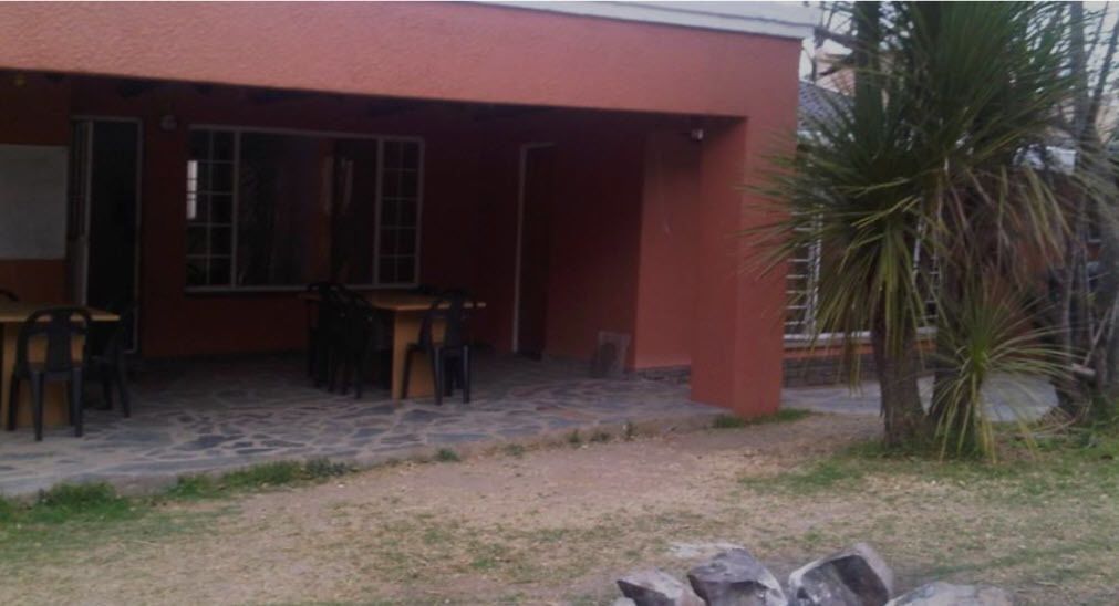 A building with a covered patio area, a stone floor, and a palm tree.