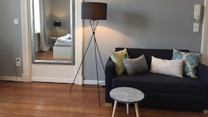 En moderne stue med en mørkeblå sofa, et rundt sofabord og en gulvlampe.