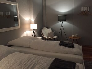 A hotel room with a bed, a chair, a small table, and two floor lamps.
